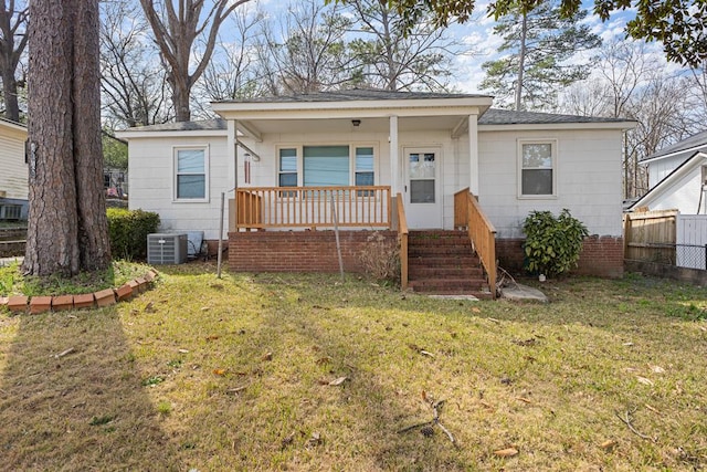 bungalow-style home with a front lawn, fence, covered porch, and central AC