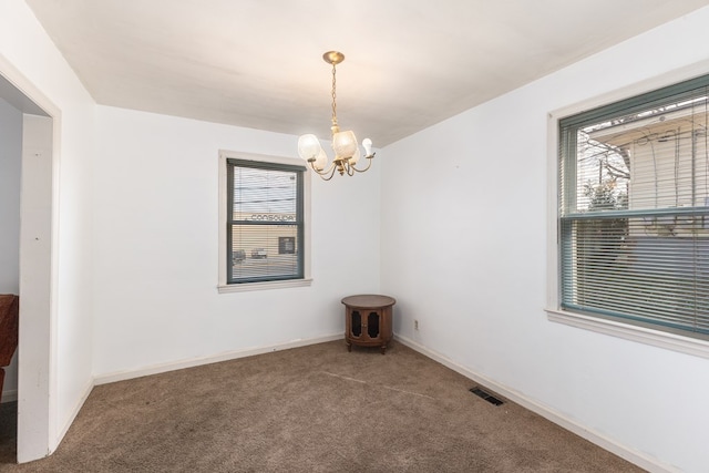 carpeted spare room with visible vents, baseboards, and an inviting chandelier