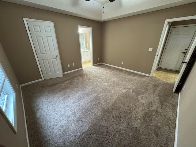 unfurnished bedroom with ceiling fan, light colored carpet, and ensuite bath