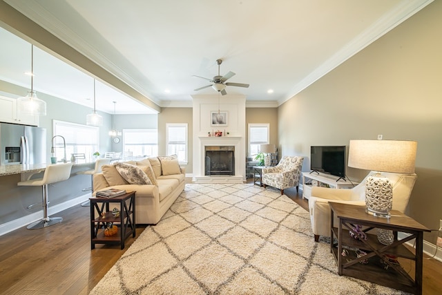 living room with ceiling fan, a fireplace, crown molding, and light hardwood / wood-style flooring