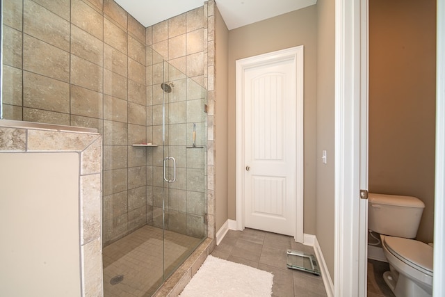 bathroom featuring toilet, tile patterned floors, and a shower with shower door