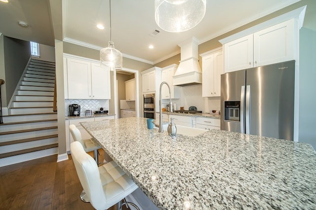 kitchen featuring custom exhaust hood, decorative backsplash, appliances with stainless steel finishes, and white cabinetry