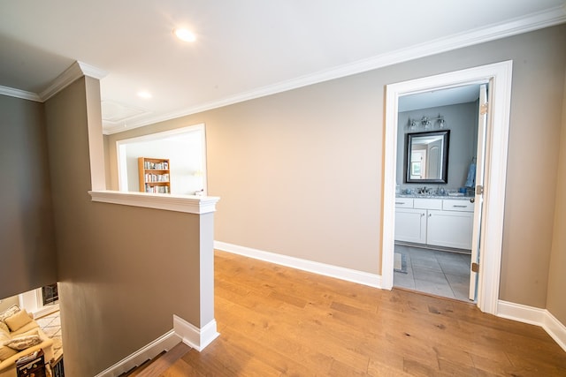 corridor with ornamental molding and light hardwood / wood-style floors