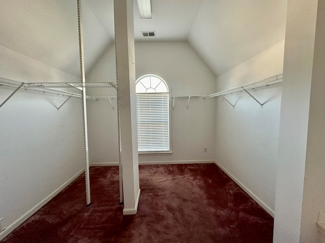 walk in closet featuring dark carpet and lofted ceiling