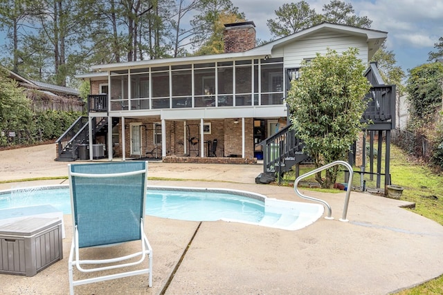 outdoor pool featuring stairs, a patio area, a sunroom, and a wooden deck