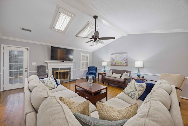 living room with visible vents, vaulted ceiling with beams, ceiling fan, a tile fireplace, and wood finished floors