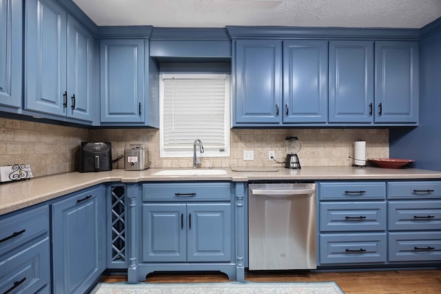 kitchen with blue cabinetry, decorative backsplash, stainless steel dishwasher, dark wood-style floors, and a sink