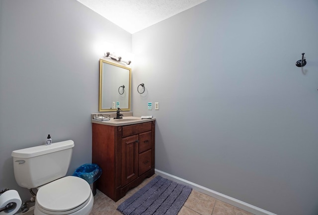 bathroom featuring tile patterned flooring, baseboards, toilet, vanity, and a textured ceiling