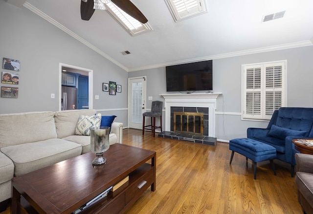 living room with lofted ceiling, ornamental molding, visible vents, and ceiling fan