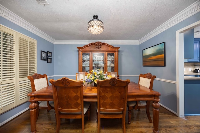 dining area featuring a textured ceiling, wood finished floors, a chandelier, and ornamental molding