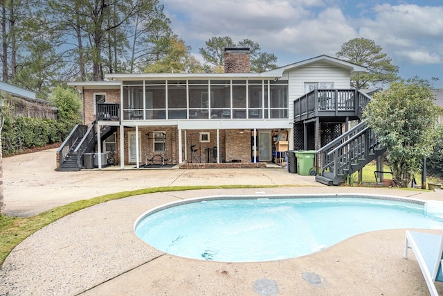 rear view of property with stairs, a patio, brick siding, and a sunroom