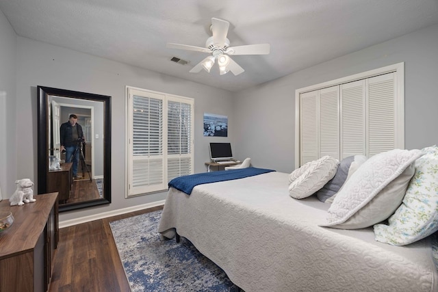 bedroom featuring a ceiling fan, dark wood-style floors, visible vents, baseboards, and a closet