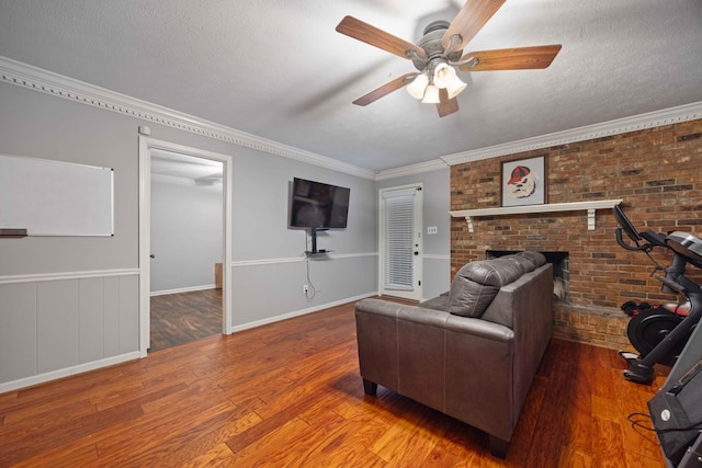 living area featuring a textured ceiling, crown molding, a ceiling fan, and wood finished floors