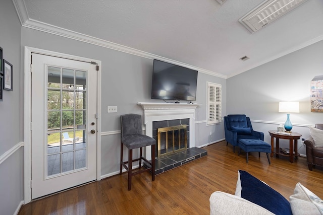 living room featuring visible vents, wood finished floors, ornamental molding, and a tile fireplace