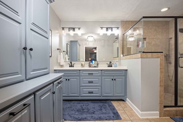 bathroom featuring tile patterned flooring, double vanity, a stall shower, and a textured ceiling