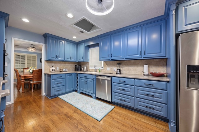 kitchen with light wood finished floors, stainless steel appliances, blue cabinets, and a sink