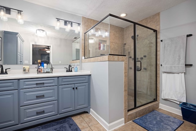 full bathroom with double vanity, a stall shower, a sink, a textured ceiling, and tile patterned floors