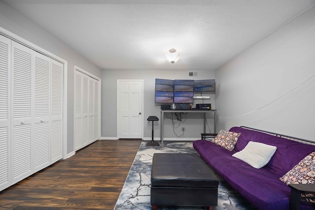 living area with visible vents, baseboards, a textured ceiling, and wood finished floors