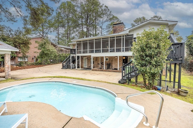 pool featuring a patio area, stairway, a deck, and a sunroom