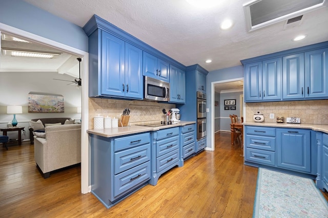 kitchen featuring blue cabinetry, appliances with stainless steel finishes, light countertops, and light wood-style floors