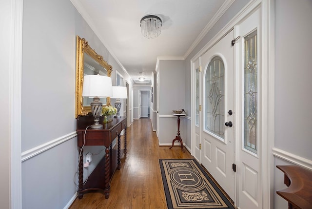 foyer featuring baseboards, wood finished floors, and crown molding