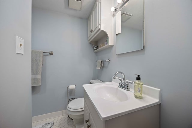 half bathroom featuring tile patterned floors, baseboards, toilet, and vanity