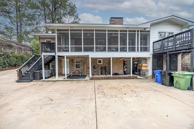 back of house with a patio, stairway, a sunroom, brick siding, and a chimney