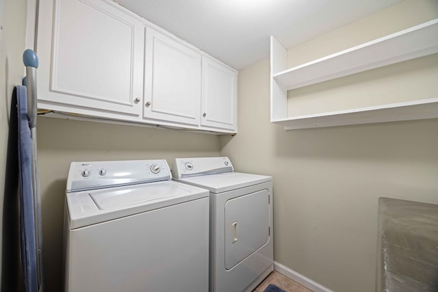 washroom featuring baseboards, cabinet space, and independent washer and dryer