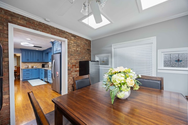 dining area featuring brick wall, a skylight, light wood-type flooring, and crown molding