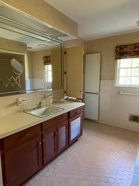 bathroom with vanity, a healthy amount of sunlight, and tile walls