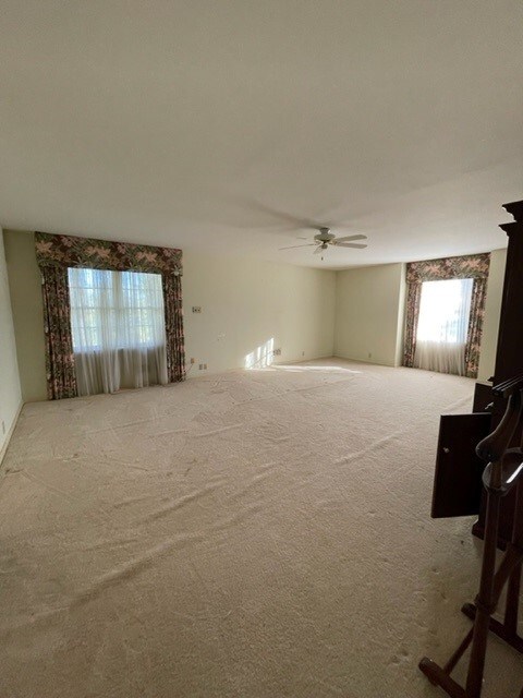 empty room featuring ceiling fan and carpet