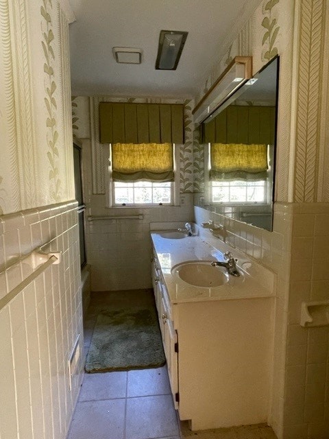 bathroom with tile patterned flooring, vanity, a wealth of natural light, and tile walls