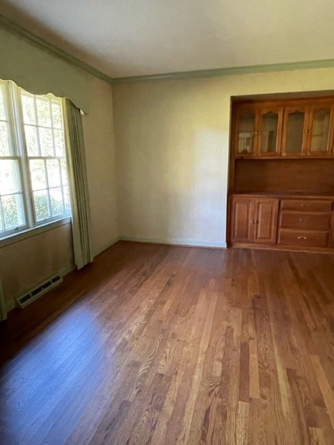 spare room featuring wood-type flooring and ornamental molding