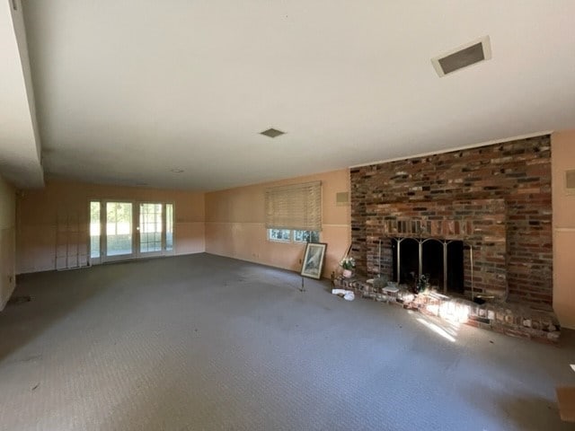 unfurnished living room with carpet and a brick fireplace