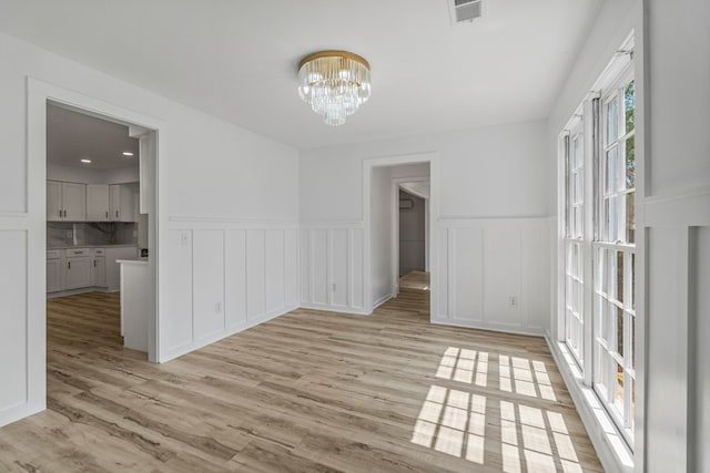 4975 Glacier Dr, Columbus, GA 31907 - unfurnished room featuring wainscoting, a chandelier, light wood-style floors, and a decorative wall