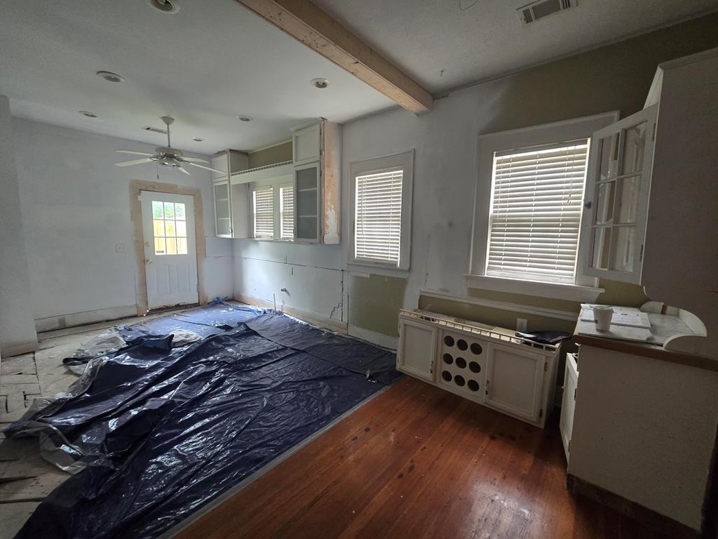 living area featuring ceiling fan, beamed ceiling, dark wood-style floors, and visible vents