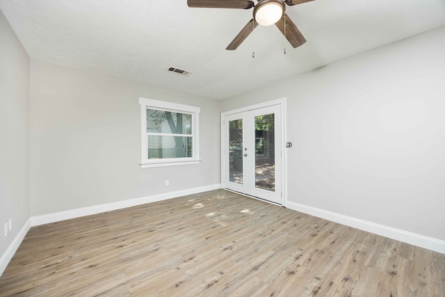 empty room with french doors, light wood-type flooring, a textured ceiling, and ceiling fan