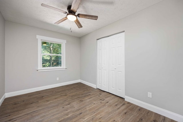 unfurnished bedroom featuring a closet, ceiling fan, hardwood / wood-style floors, and a textured ceiling