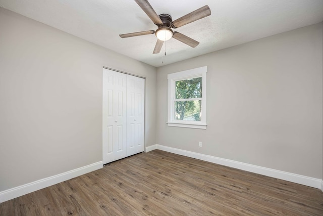 unfurnished bedroom with a textured ceiling, a closet, dark hardwood / wood-style floors, and ceiling fan