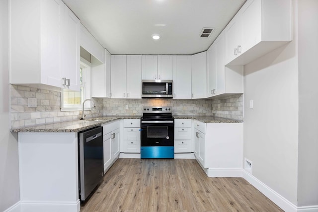 kitchen with white cabinetry, light hardwood / wood-style floors, and appliances with stainless steel finishes