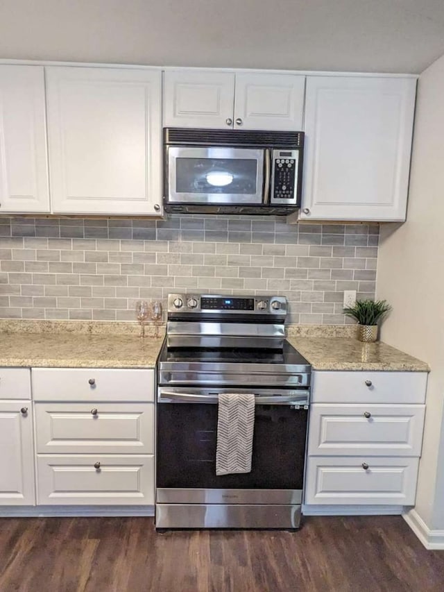 kitchen with white cabinetry, dark wood-type flooring, tasteful backsplash, light stone counters, and appliances with stainless steel finishes