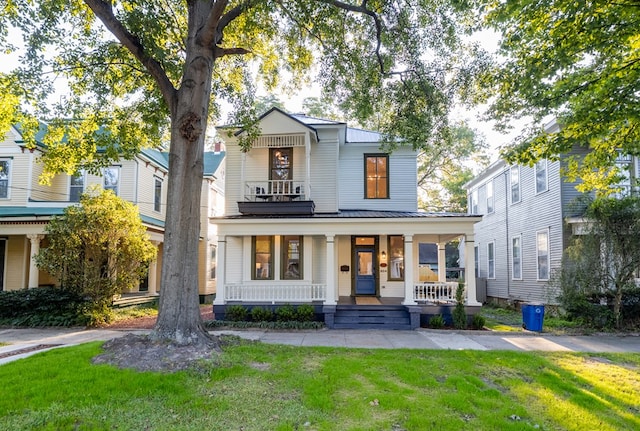 view of front of property featuring covered porch, a balcony, and a front lawn