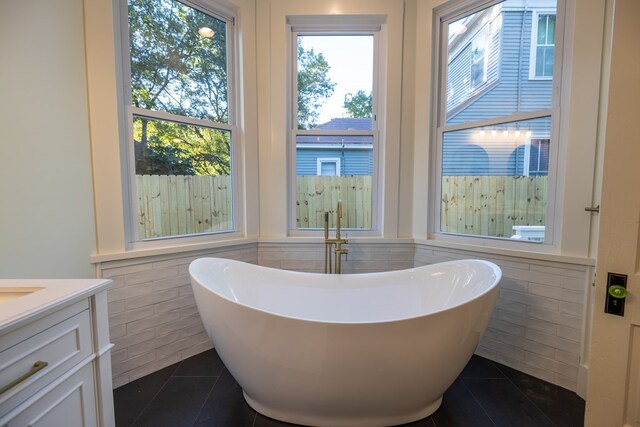 bathroom featuring tile patterned flooring, a bathtub, tile walls, and vanity