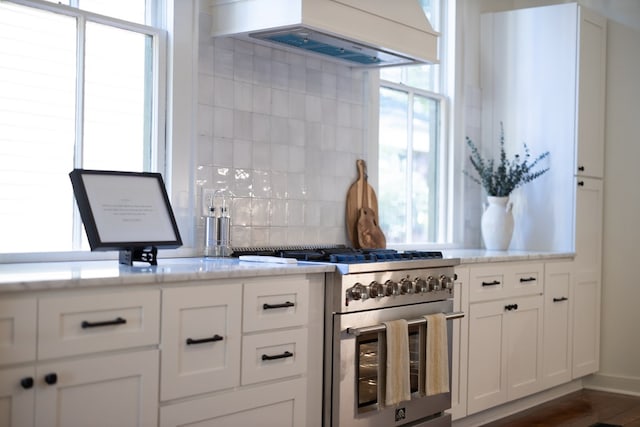 kitchen featuring backsplash, wall chimney exhaust hood, dark wood-type flooring, double oven range, and white cabinetry