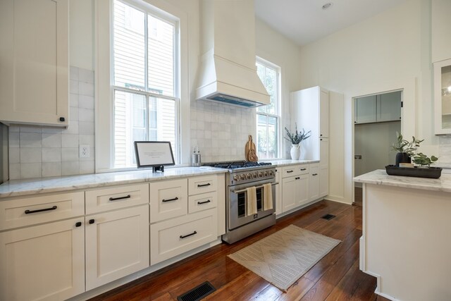 kitchen featuring light stone counters, dark hardwood / wood-style floors, premium range hood, range with two ovens, and white cabinets