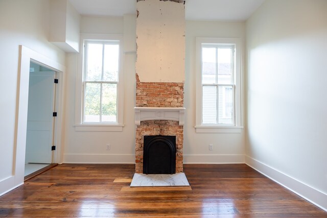 unfurnished living room with plenty of natural light, dark hardwood / wood-style flooring, and a fireplace