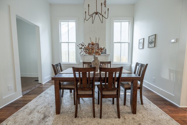 dining space with dark hardwood / wood-style flooring and an inviting chandelier