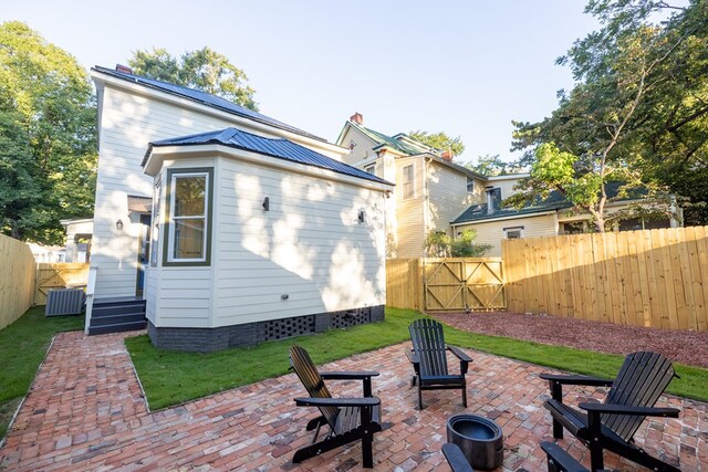 rear view of house with a patio area, cooling unit, and a fire pit