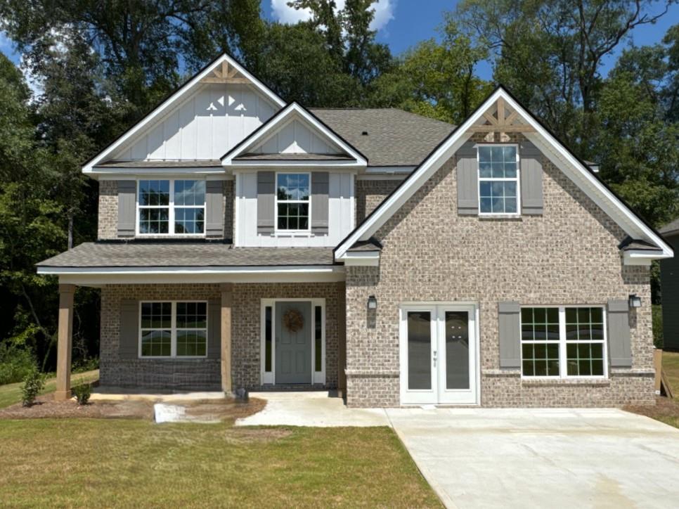 view of front of home featuring covered porch, a front lawn, french doors, board and batten siding, and brick siding