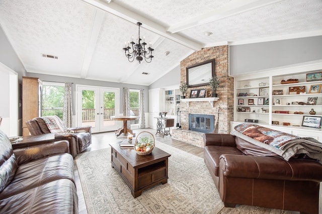6909 Trapper Way, Midland, GA 31820 - living area featuring a textured ceiling, wood finished floors, a fireplace, a chandelier, and french doors